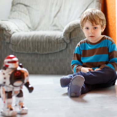 Evde, robot oyuncak ile kapalı oynayan küçük sarışın çocuk.