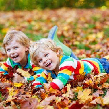 İki küçük renkli giyim sonbahar yaprakları döşeme çocuklar çocuk