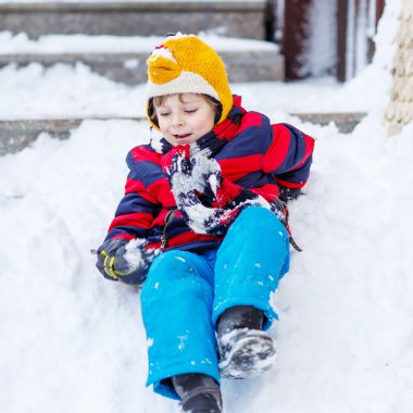 kar, outd üzerinde sürme ile eğleniyor renkli giysiler içinde çocuk evlat