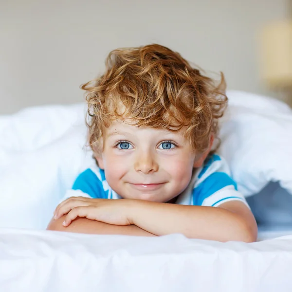 Adorable kid boy after sleeping in his white bed — Stock Photo, Image