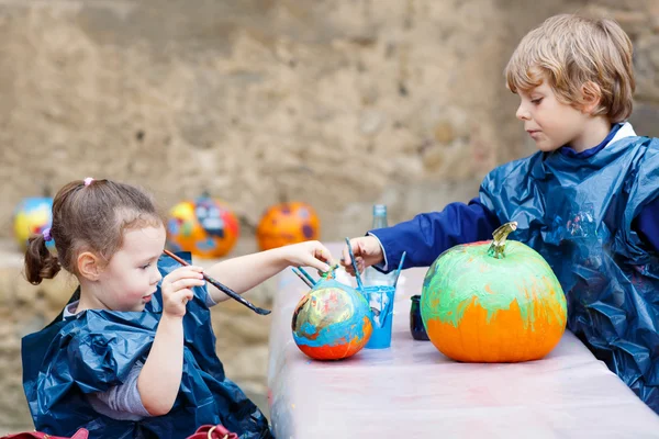 Duas crianças pequenas pintando com cores na abóbora — Fotografia de Stock