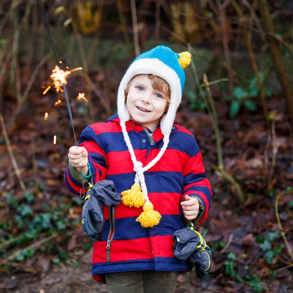 Niño pequeño con ropa de invierno sosteniendo chispa ardiente —  Fotos de Stock