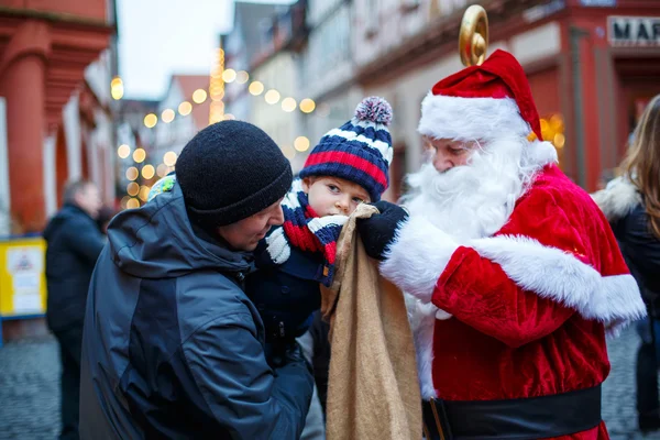 Malý chlapec batole s otcem a Santa Claus na vánoční trh — Stock fotografie