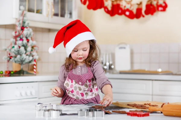 Malá holčička pečení perníku cookie v domácí kuchyni — Stock fotografie