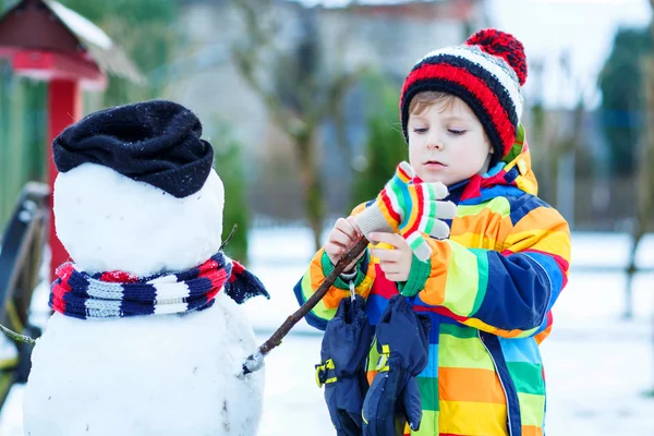 Chico gracioso haciendo un muñeco de nieve en invierno — Foto de Stock