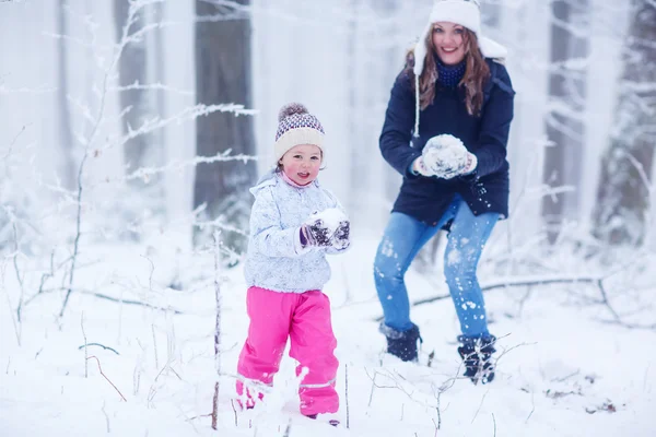 Mamma och hennes lilla barn dotter leker med snöbollar — Stockfoto