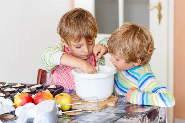 Two little kid boys baking apple cake indoors