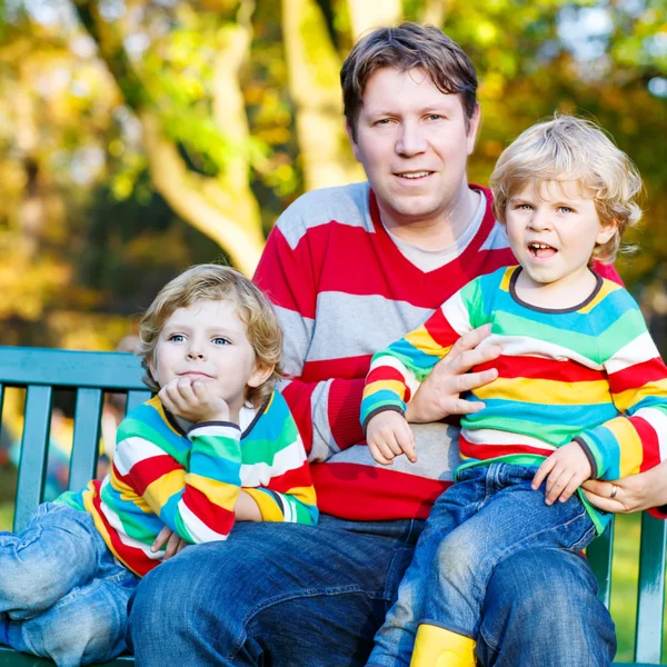 Dos niños pequeños y padre joven sentados juntos, el otoño, o —  Fotos de Stock