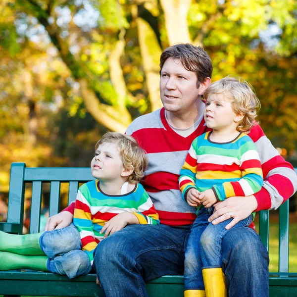 Deux petits garçons et un jeune père assis ensemble, l'automne, o — Photo