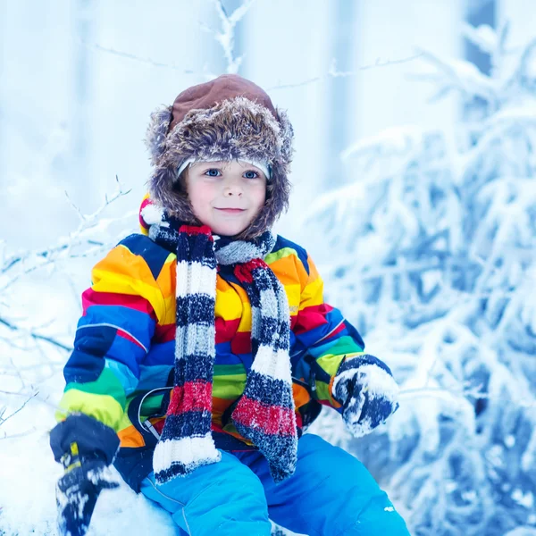 Cute little funny boy in colorful winter clothes having fun with — Stock Photo, Image