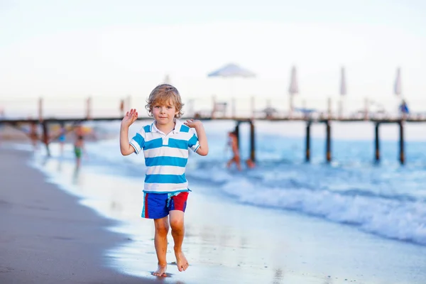 Feliz niño divirtiéndose con correr a través del agua en oc — Foto de Stock