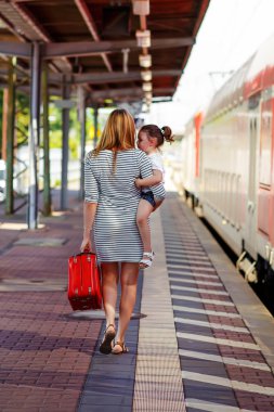 Sevimli küçük kız ve annesi bir tren istasyonu.
