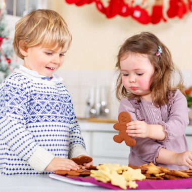 Little boy and girl, siblings, baking gingerbread cookies in dom