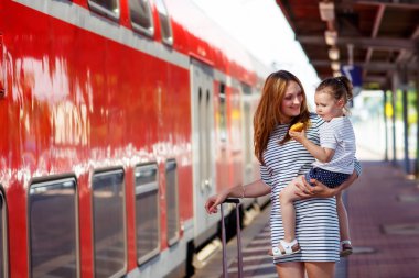 Sevimli küçük kız ve annesi bir tren istasyonu.