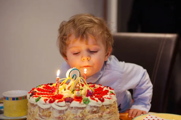 Kid celebrating birthday and blowing cake candles — Stock Photo, Image