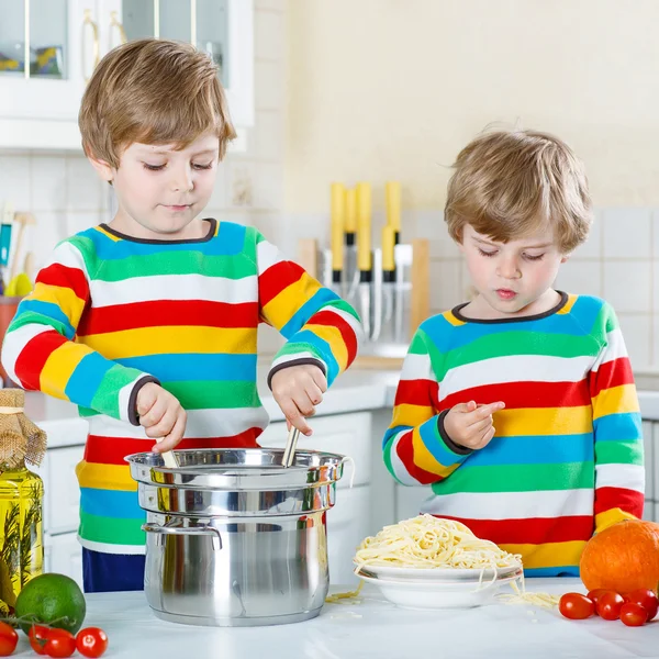 Deux petits garçons mangeant des spaghettis dans la cuisine domestique . — Photo