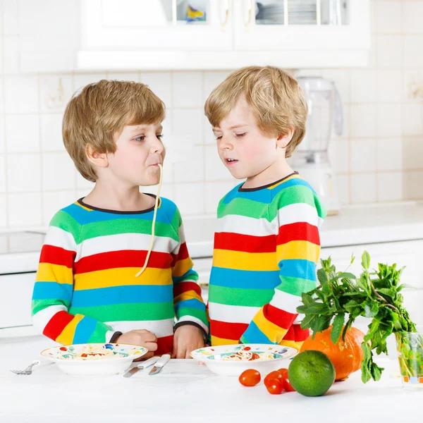 Két kis gyerek fiú eszik spagetti hazai konyha. — Stock Fotó