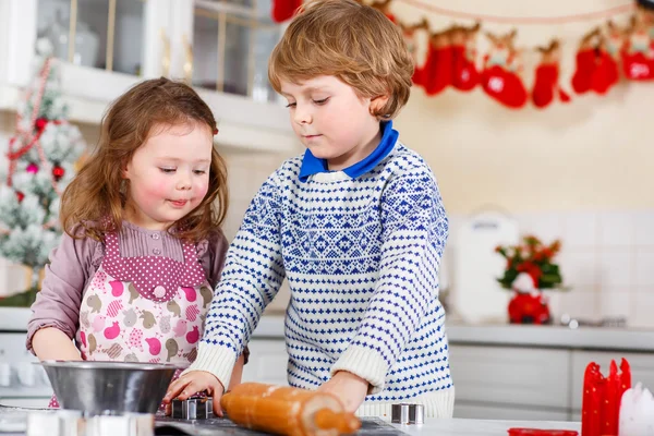 Garoto e menina fazendo biscoitos de Natal em casa — Fotografia de Stock