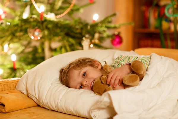 Pequeño niño rubio lindo durmiendo bajo el árbol de Navidad — Foto de Stock