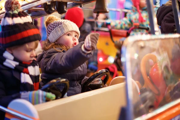 Petit garçon et fille sur un carrousel au marché de Noël — Photo