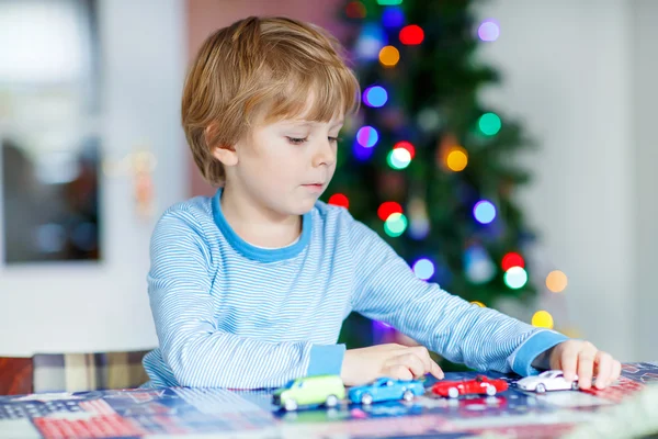 Pequena criança loira brincando com carros e brinquedos em casa — Fotografia de Stock