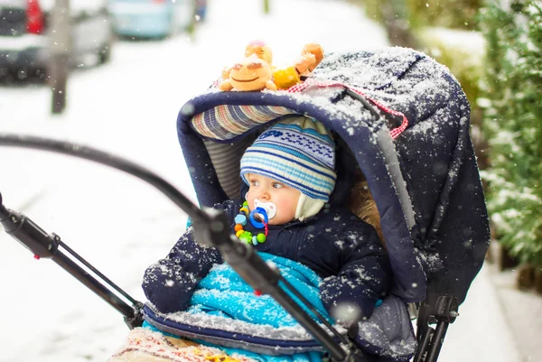 Babyjongen in pram tijdens de wintersneeuw vallen — Stockfoto