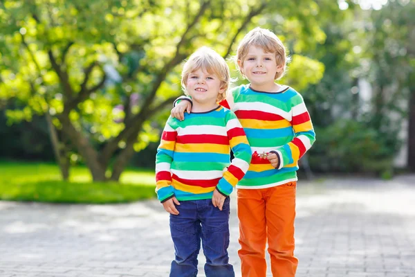 Two little kid boys in colorful clothing walking hand in hand — Stock Photo, Image
