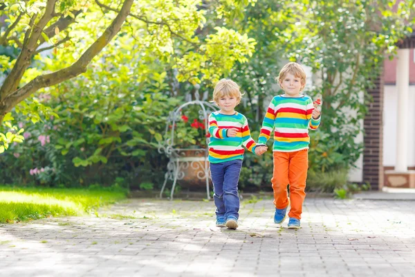 Två små syskon barn pojkar i färgglada kläder gå hand i — Stockfoto