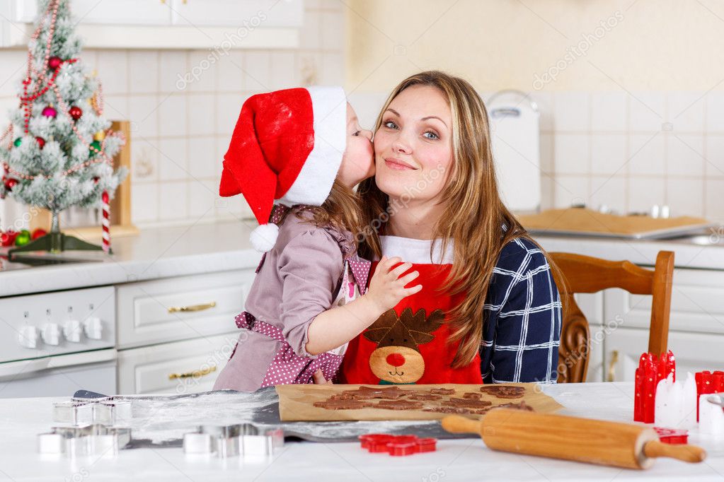 Mother and little kid girl baking gingerbread cookies for Christ