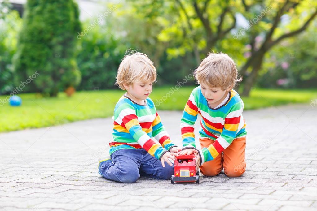 Two little friends playing with red school bus