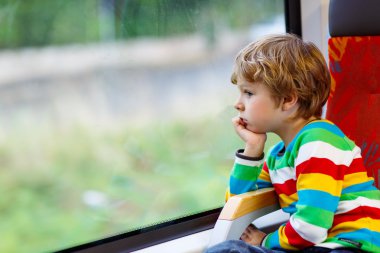 Little boy sitting in train and going on vacations