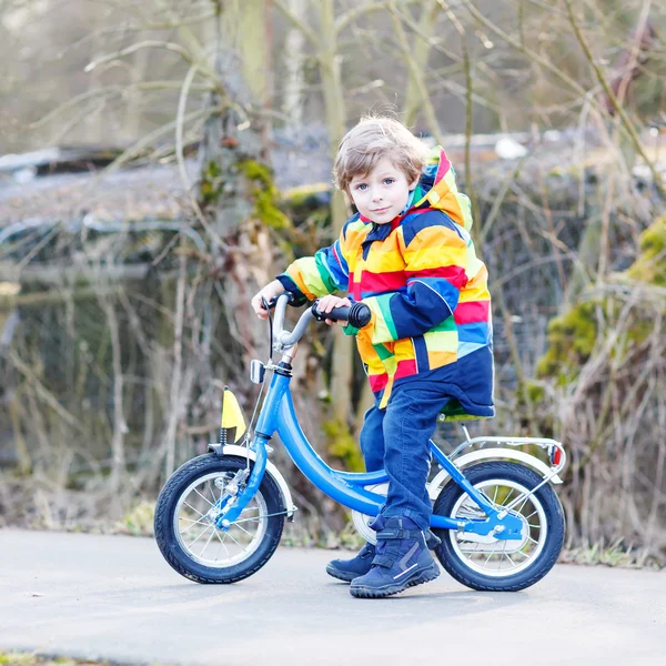 Gyerek fiú bukósisak és színes esőkabát lovaglás kerékpár, szabadb — Stock Fotó