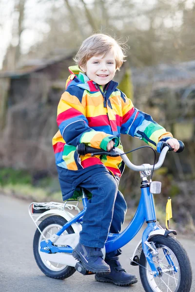 子供の安全ヘルメットのカラフルなレインコート自転車に乗って、ピンクのディルドと少年 — ストック写真