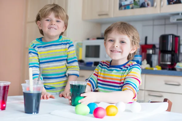 Zwei kleine blonde Jungen färben Eier für die Osterfeiertage — Stockfoto