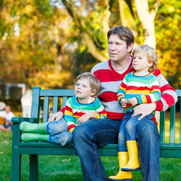 Deux petits garçons et un jeune père assis ensemble, l'automne, o — Photo