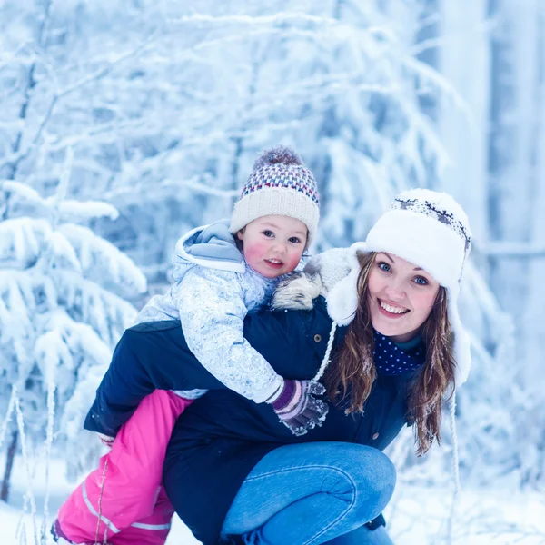 Porträtt av en liten flicka och hennes mor i vintermössa i snö f — Stockfoto