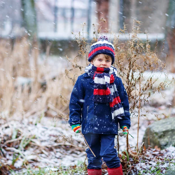 Söt liten rolig pojke i färgglada vinterkläder har roligt med — Stockfoto