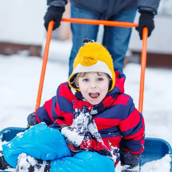 Funny kid boy having fun with riding on snow shovel, outdoors — Stock Photo, Image