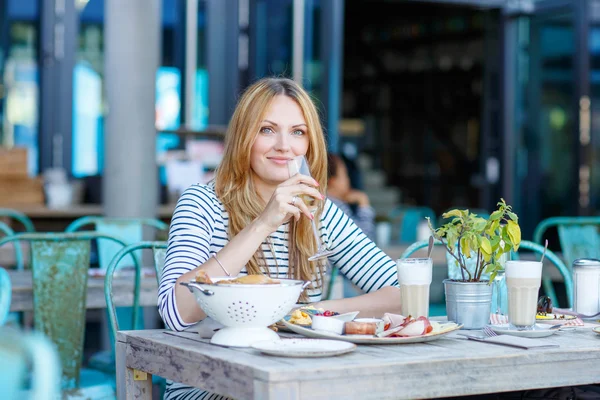 Молодая женщина, завтракающая в кафе на открытом воздухе — стоковое фото