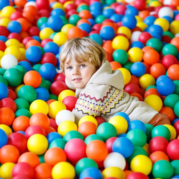 Kind spielt auf Spielplatz mit bunten Plastikbällen — Stockfoto