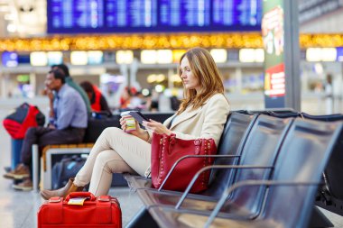 kadın uluslararası havaalanında uçuş terminalinde bekliyor