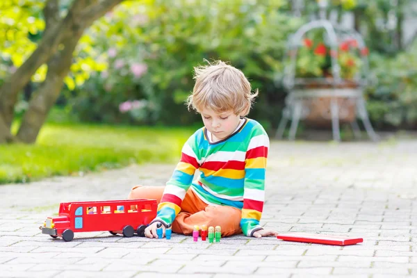 Ativo garoto brincando com ônibus escolar vermelho e brinquedos — Fotografia de Stock