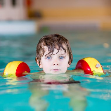küçük çocuk çocuk swimmies bir kapalı havuzda yüzmek için öğrenme ile