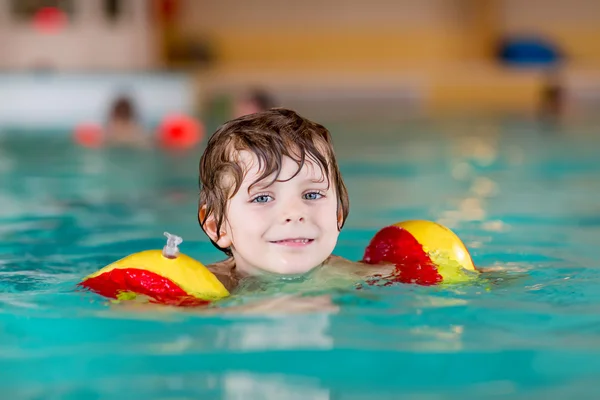 Garotinho com nadadores aprendendo a nadar em uma piscina interior — Fotografia de Stock