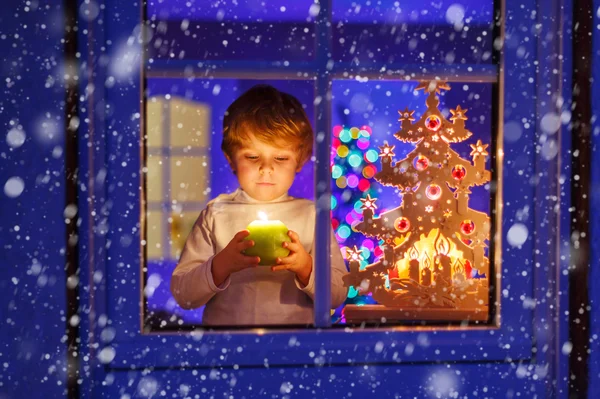 Ragazzino in piedi vicino alla finestra a Natale e tenendo — Foto Stock