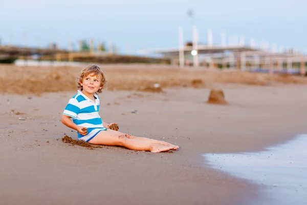 Boldog kis gyerek fiú birtoklás móka-val homokvárat, óceán — Stock Fotó