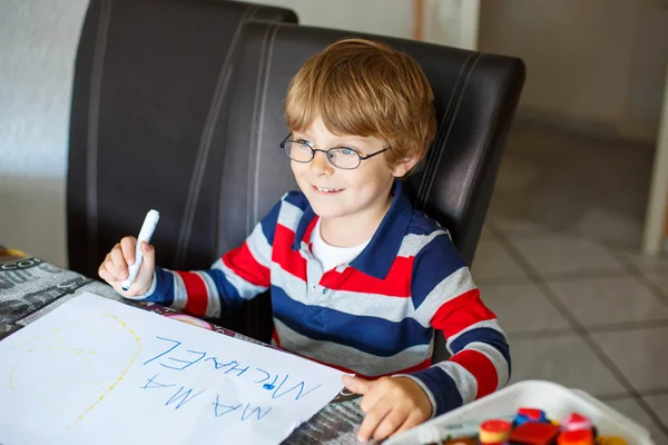 Kid boy in glasses making school homework at home — 图库照片