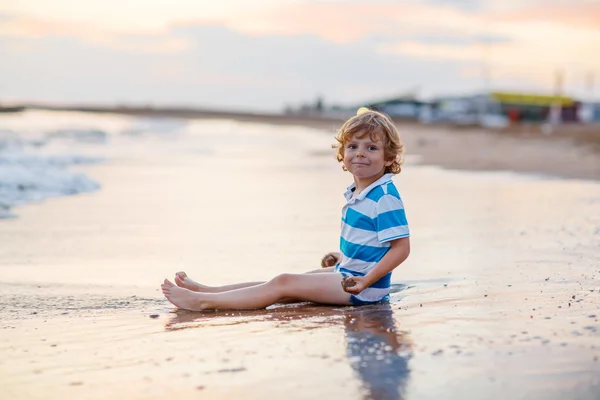 Joyeux petit garçon s'amuser avec le château de sable par l'océan — Photo