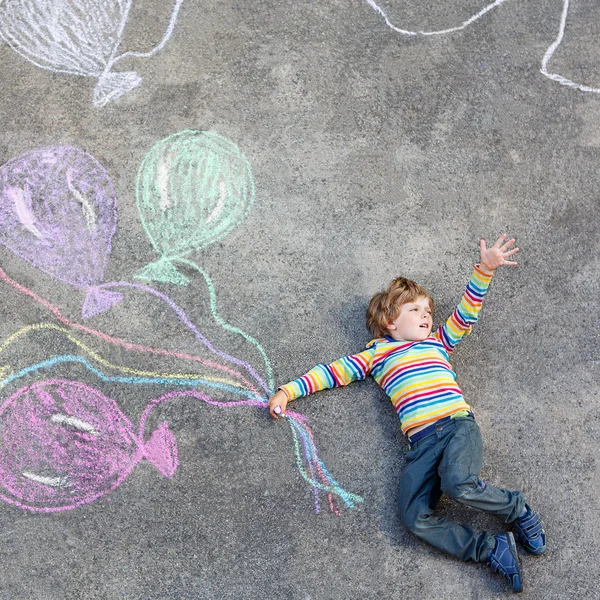 Kid jongen hebben plezier met kleurrijke ballonnen tekening met krijt — Stockfoto