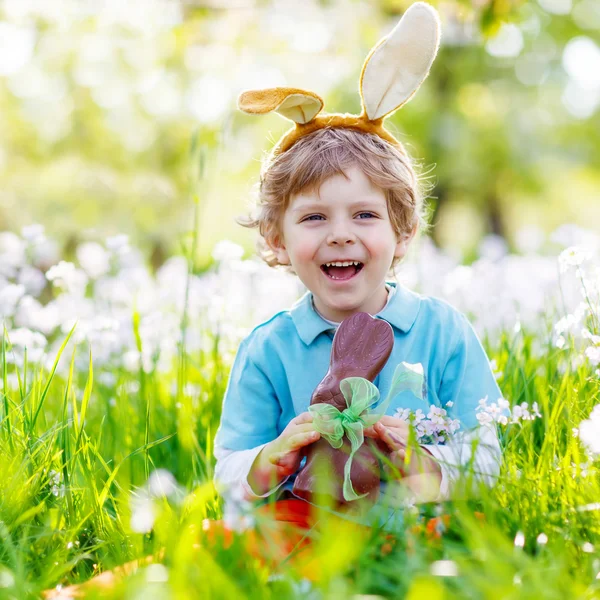 Liten unge pojken äta choklad Easter bunny utomhus — Stockfoto